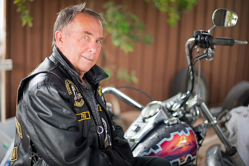 Roy 'Shorty' Mawer rests against his customised Harley Davidson motorcycle inside the garage of his Cairns home.