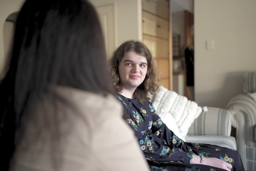 A young woman looks at her mother and smiles softly.