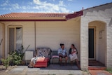 Two women sit out the front of a brick home in suburban Perth.