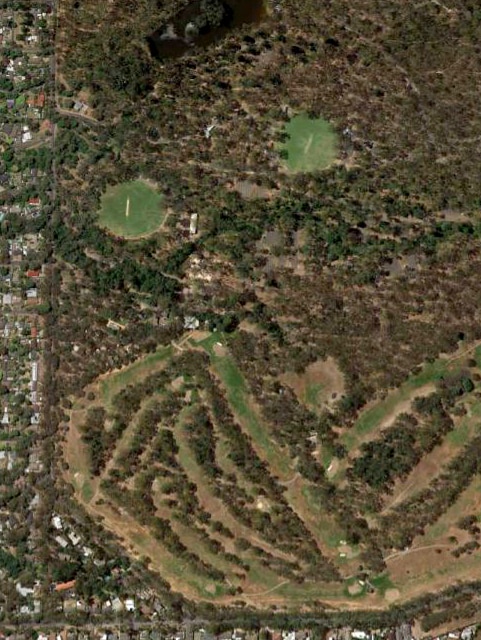 An overhead photograph of bushland with several fairways and ovals.