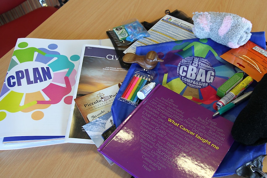 Cancer support bag with its contents displayed on a wooden table.