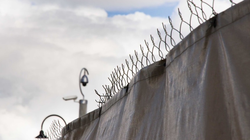 A barbed wire fence covered with a black tarpaulin.