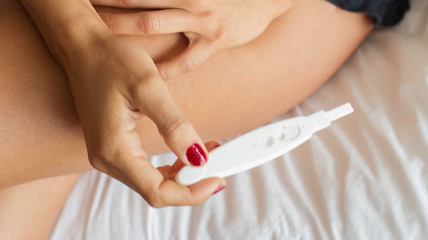 A woman looking at a pregnancy test.