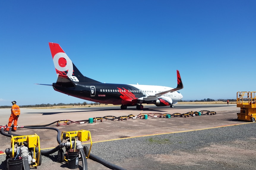A Boeing 737 Fireliner large air tanker on the runway at Busselton airport, with refuelling gear in the foreground.