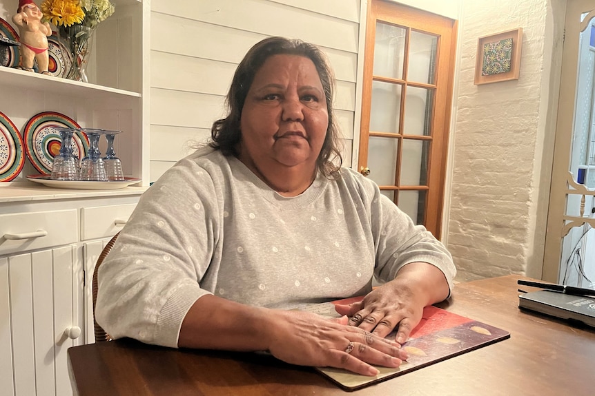 An elderly First Nations woman sits at her home in York with her hands on the table.