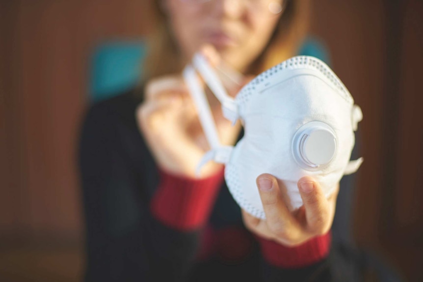 Woman holds respirator in her hands