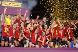 A team of soccer players wearing red and blue celebrates after winning a competition