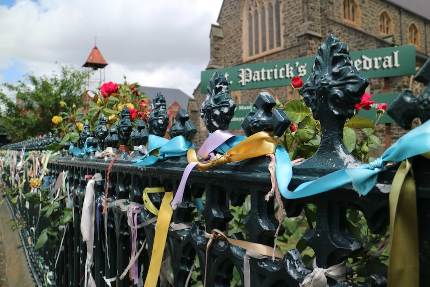 Hundreds of colourful ribbons tied to a fence outside a church