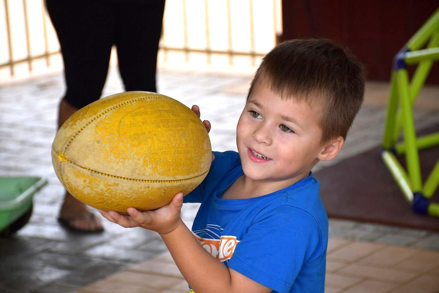 A young boy holds a football.