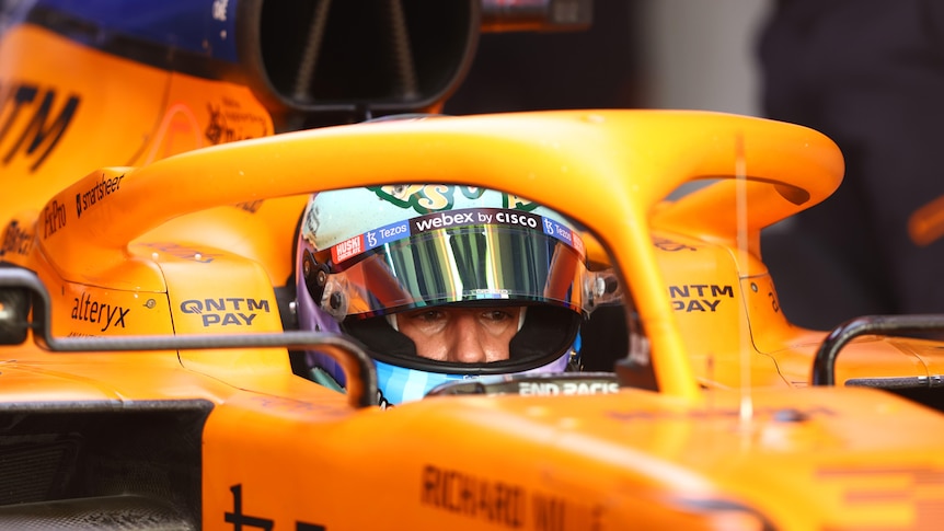 Race driver with is helmet on sitting in his open-wheel car.