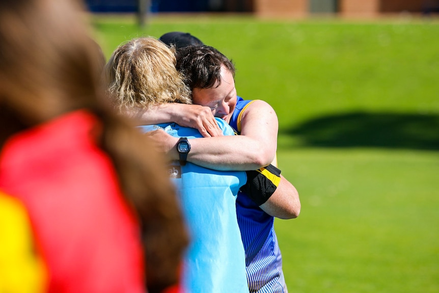 An athlete hugs an official at the games.