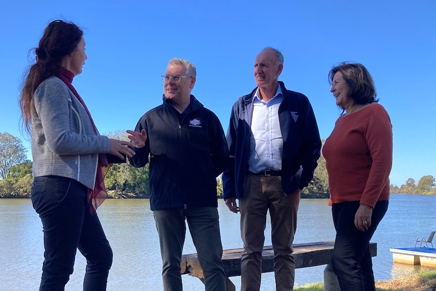 four people stand near a river