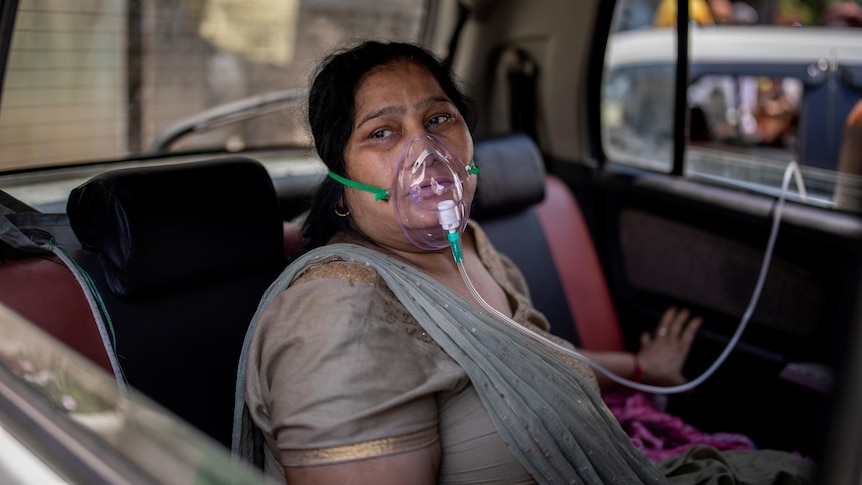 A COVID-19 patient sits inside a car and breathes with the help of oxygen provided by a Gurdwara.