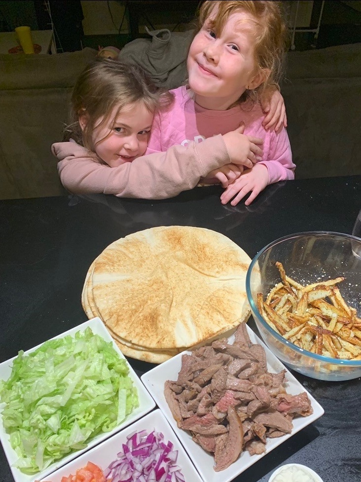 Two girls in front of a plate of healthy food.