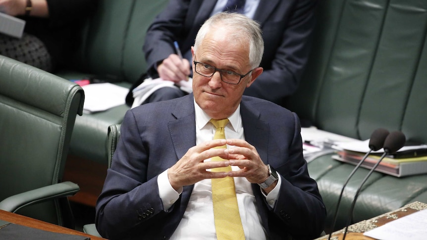 Malcolm Turnbull sits in the House of Representatives during Question Time. He is smiling with his hands clasped.