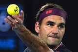 A male tennis player holds the ball in the air as he prepares to serve at the Australian Open.