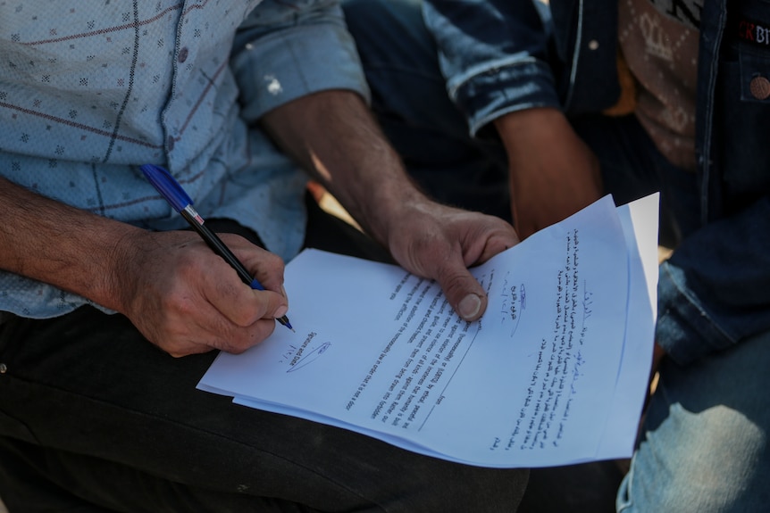 A man signs a pledge to stand against homosexuality or LGBTQ, outside a mosque.