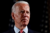 US presidential candidate Joe Biden, wearing a dark suit and red tie, frowns and looks off into the distance