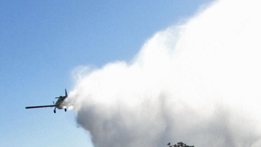 A plane drops water over bushfires in Perth