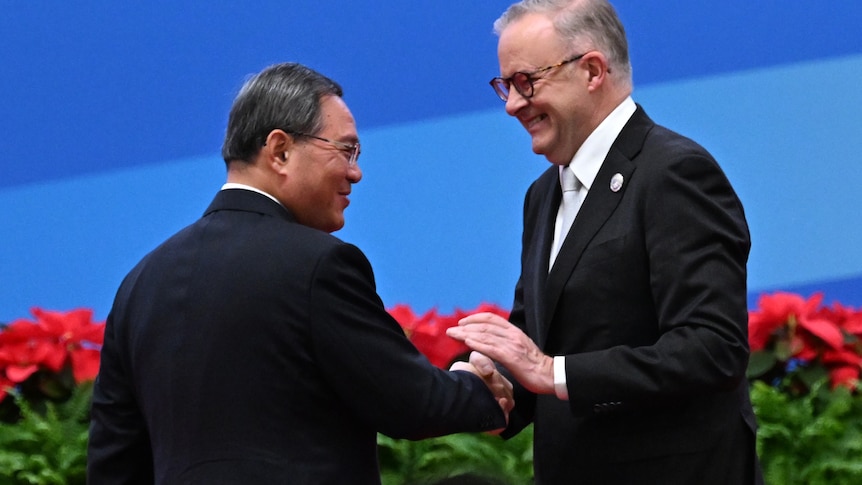 Anthony Albanese and Li Qiang shake hands against a blue backdrop.