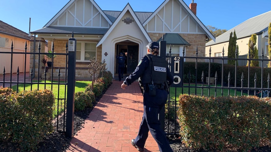 Police officers enter a house at Lockleys.