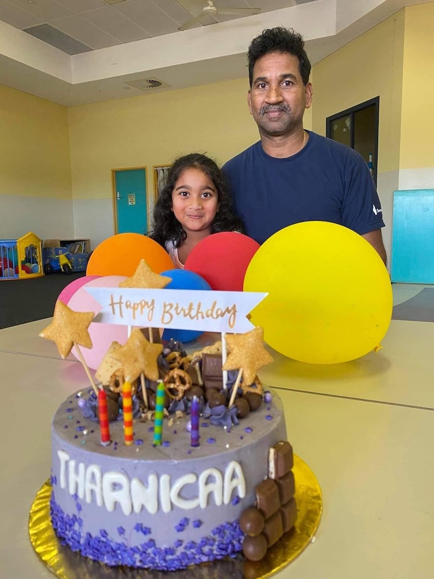 Kopica Murugappan and Nades Murugappan sit by a table with balloons and a birthday cake