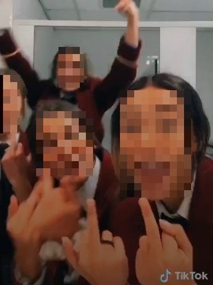 School students with their faces blurred give the finger.