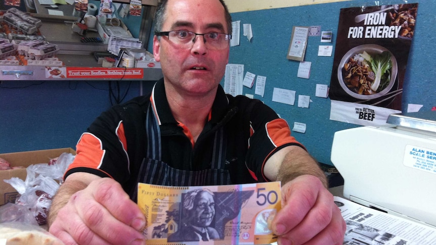 Snug Butcher holds a counterfeit $50