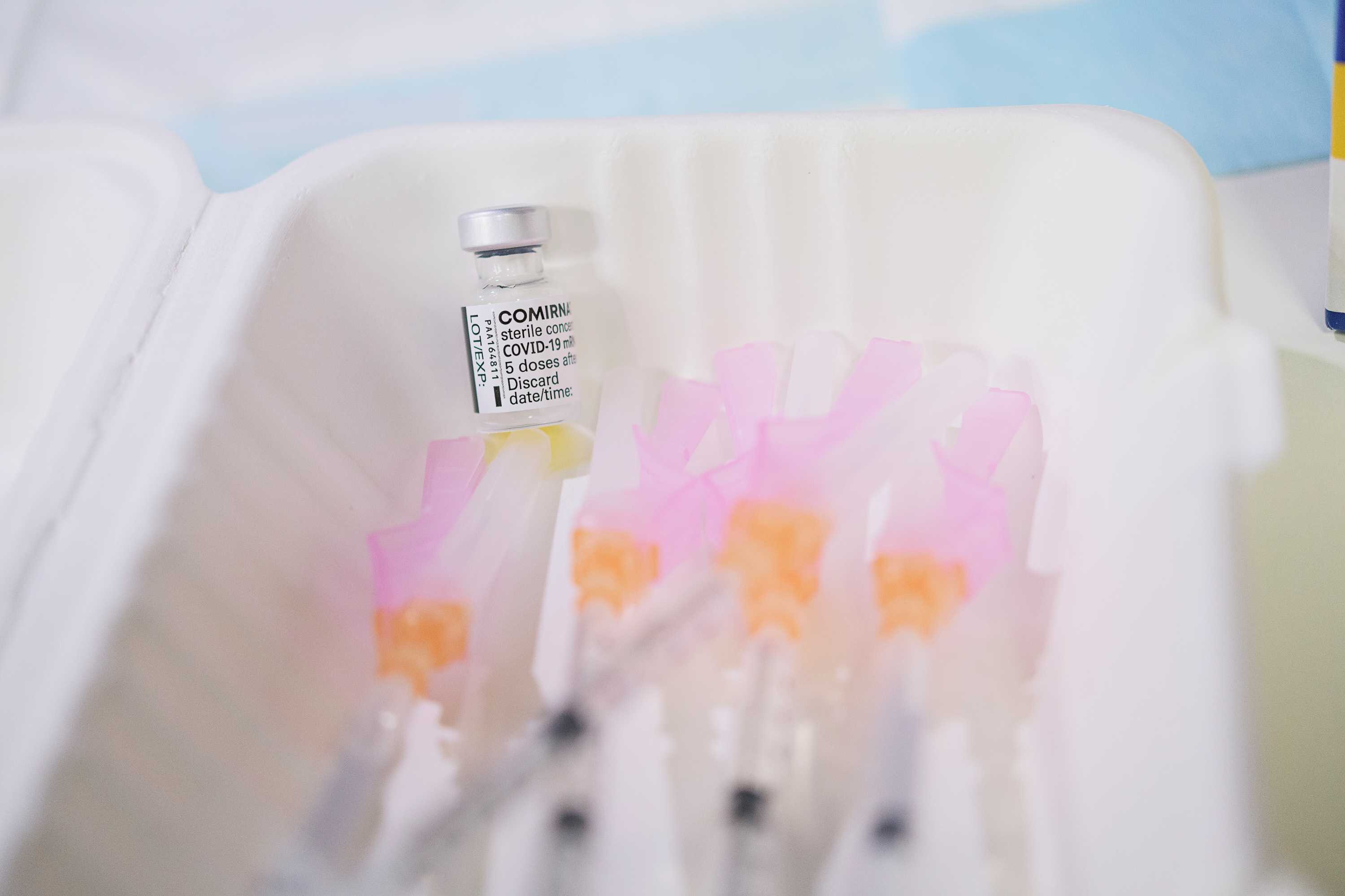 A vial of the Pfizer vaccine sits near needles.