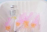 A vial of the Pfizer vaccine sits near needles.