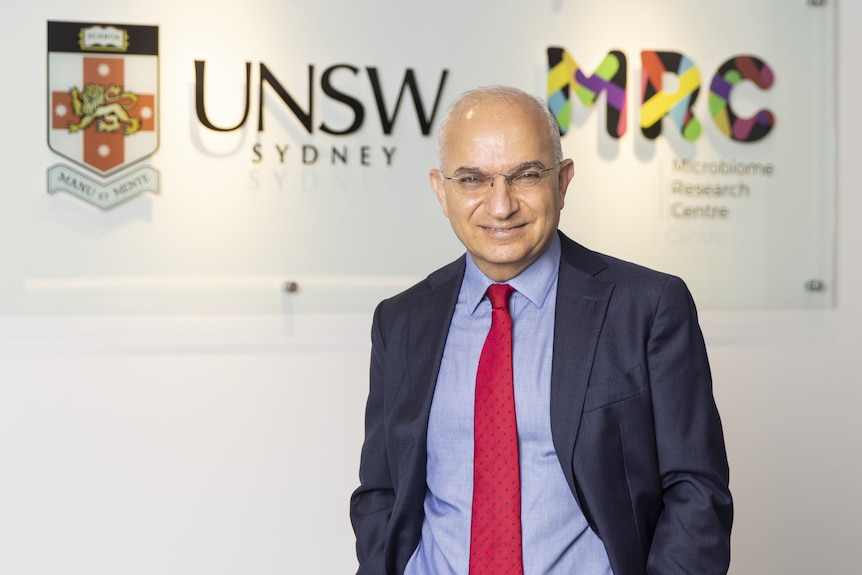 A man in a suit in front of a UNSW sign