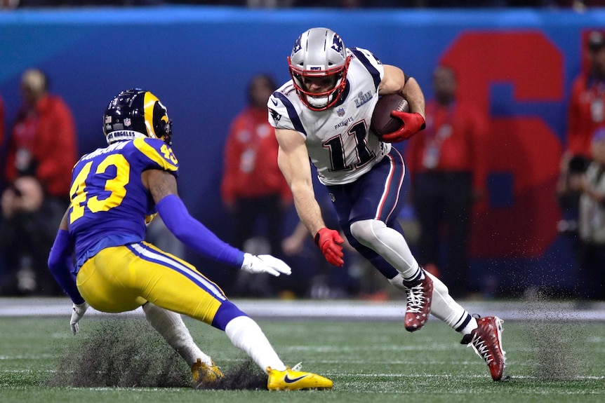 Julian Edelman steps off his right foot with the ball in his left hand as he attempts to beat the tackle of John Johnson III.