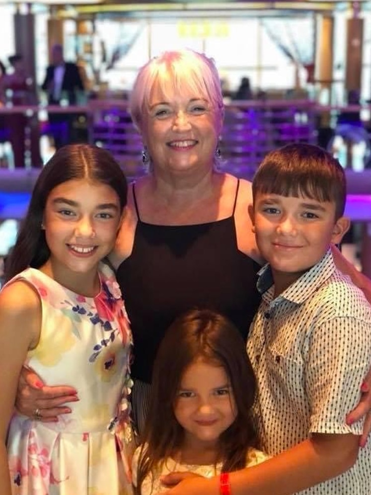 A woman and her three grandchildren pose for a photo