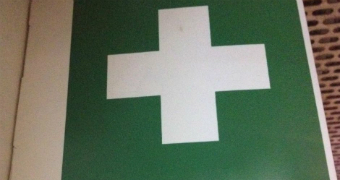 A white medical cross on a green background.