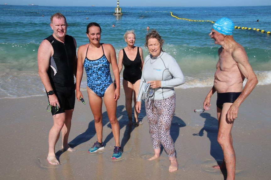 Chantal Barrett (blue bathers) stands on Cottesloe Beach with a group of other swimmers.