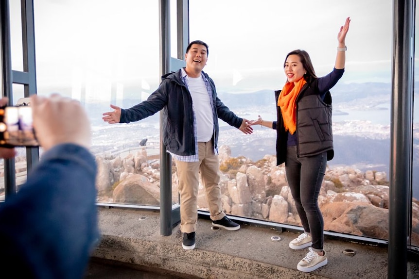 Asian tourists pose for photo at Mt Wellington summit viewing shelter, photo from Tourism Australia.