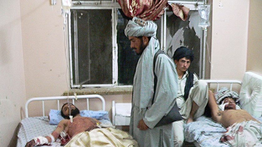 People sit with two of the wounded lying in a hospital in Kandahar
