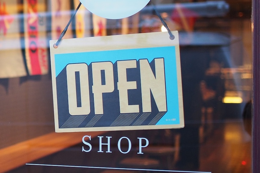 'Open' sign hanging in shop window.