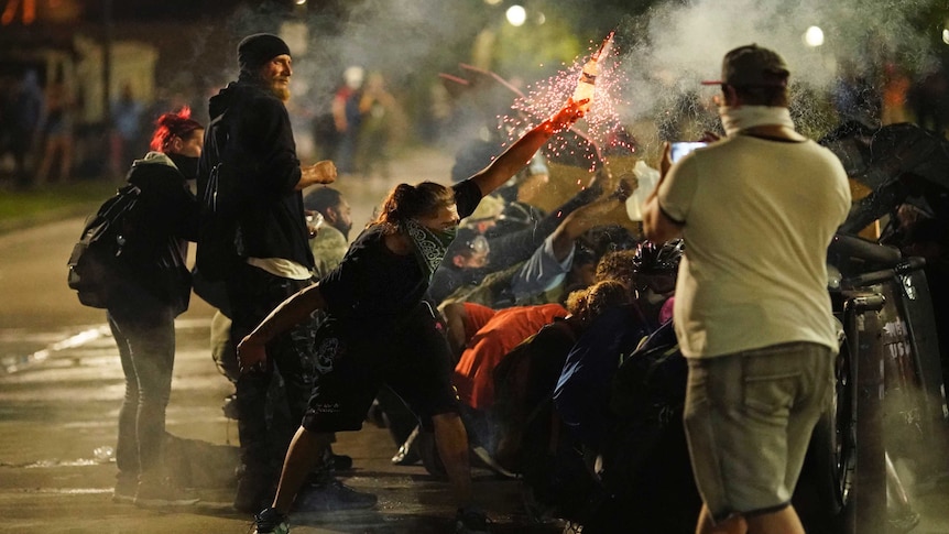 A protester holds a bottle of sparkler as protester shelter from police during a protest in Kenosha, Wisconsin.