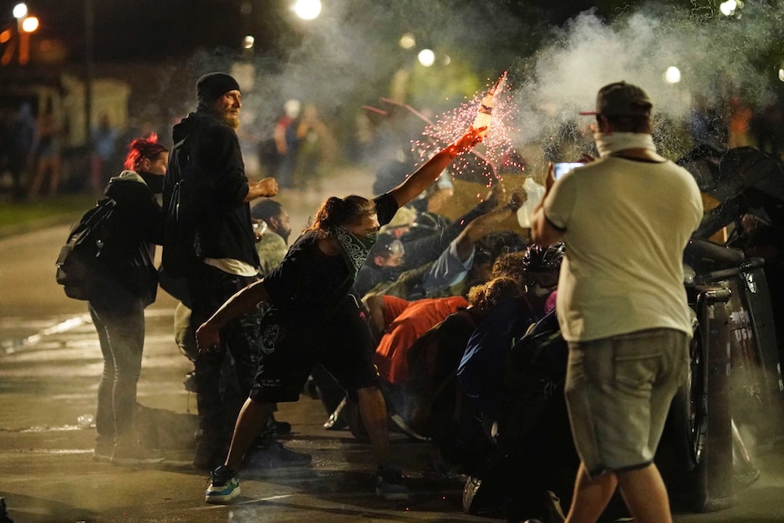 A protester holds a bottle of sparkler as protester shelter from police during a protest in Kenosha, Wisconsin.