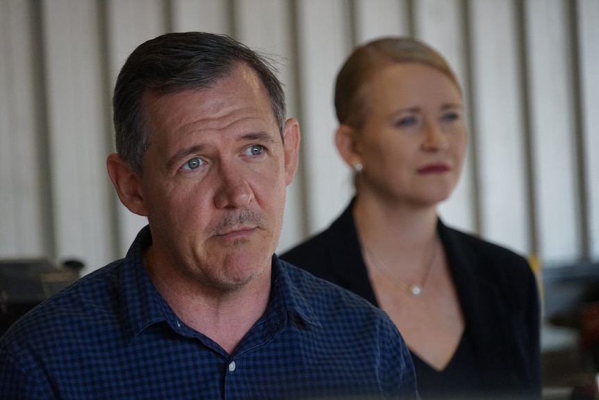 Michael Gunner and Nicole Manison looks across the camera standing in front of white curtains at a press conference.