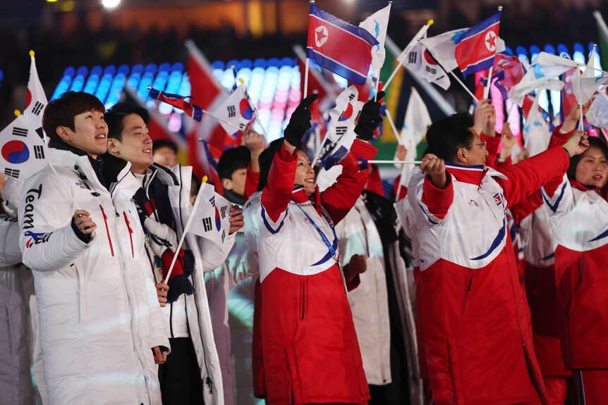 South and North Korean athletes wave flags at the Olympic Winter Games closing ceremony.