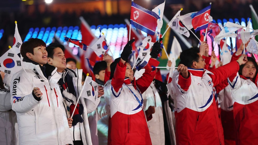 South and North Korean athletes wave flags at the Olympic Winter Games closing ceremony.