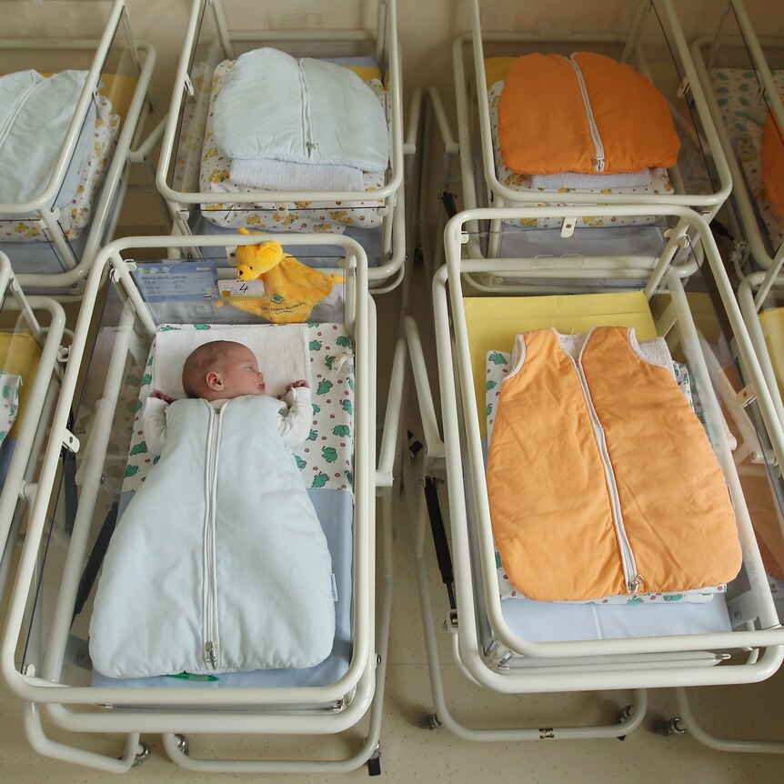 A newborn baby among empty baby beds in a German hospital