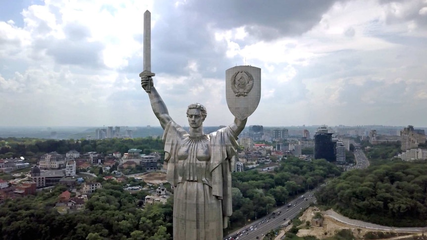 A close up of a stainless steel statue in Keiv, Ukraine depicting a woman holding a sword and a shield.