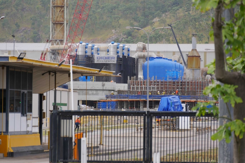 A crane and workers on scaffolding can be seen at Sun Metals and new bright blue vats