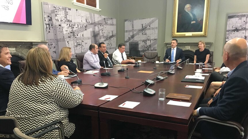 Peter Malinauskas sitting at a large table with a dozen union members and businesses.