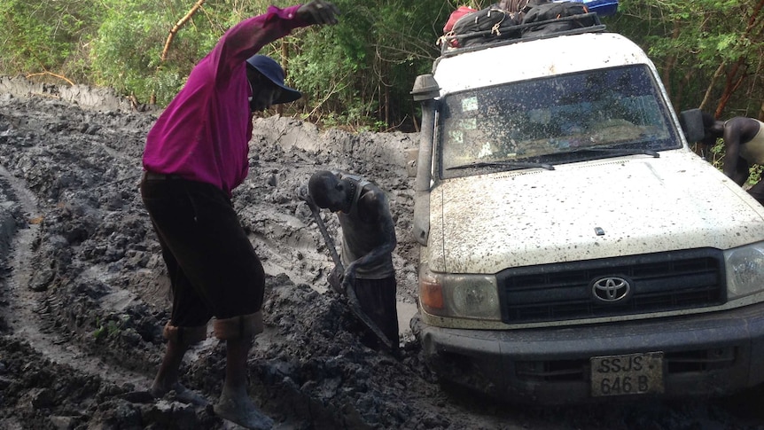 Two men work to free a 4WD stuck on a muddy track