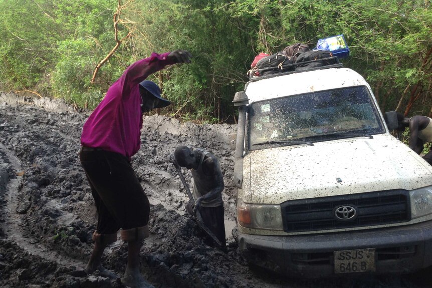 Two men work to free a 4WD stuck on a muddy track