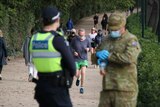 A police officer and an ADF member in the foreground with people running and walking in front of them.